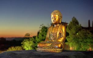 bronze Buddha figurine on stone at dusk