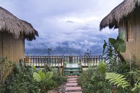 huts in tropical garden in front of scenic misty mountains, vietnam