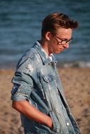 young man with glasses on the beach on a sunny day