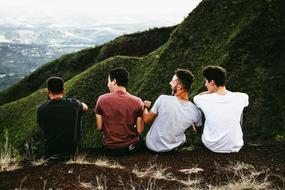 four young boys sitting on Mountain at scenic landscape