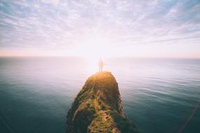 silhouette of a man on a cliff on the ocean