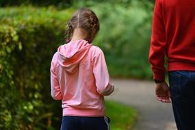 Child girl walking side by side with Father in park