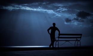 silhouette of a man at the bench against the night sky
