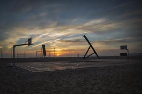 photo of a basketball field on the beach at sunset