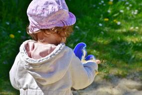 girl with a sand toy stands with her back