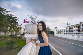 girl in dress posing at fence in town