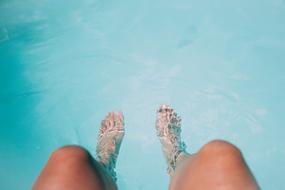 feet in the pool water on a sunny day