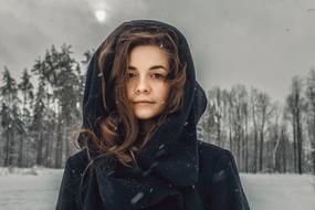 girl in a raincoat on a background of winter forest