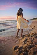 girl in a summer dress on the sandy seashore