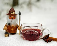 Beautiful, cute and colorful figure of the elf, with the beautiful glass of mulled claret, on the snow, in the winter