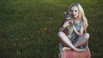 girl with a cat on the background of a green meadow