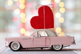 red heart on vintage car on blurred background