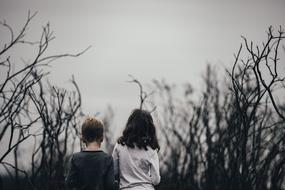 brother and sister walk among the bare bushes