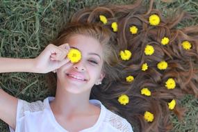 photo of a girl with yellow flowers in her hair lying on the grass