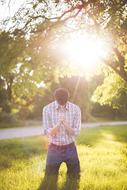 a man prays with his back to the bright morning sun