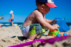baby Boy plays with toy excavator on sand