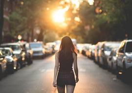 photo of a girl walking along the roadway against the background of the evening sun