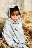 portrait of a poor hungry Indian child in the hay