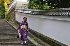 girl in purple kimono goes down the stairs in Kyoto, Japan