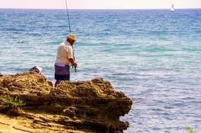 fisherman on a cliff by the sea