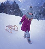 child with a sled in the snow