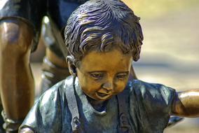 Shiny, bronze sculpture of the boy, in Fort Smith, Arkansas River Valley in USA, in sunlight