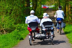 people riding Double Rider tricycle on path in park