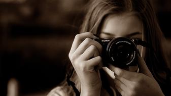 girl holds sony Photo camera at face