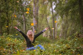 young girl throwing up leaves in forest