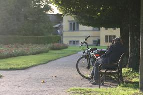 elderly man on a park bench and a parked bicycle