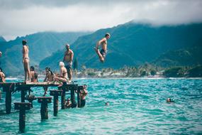 people jump into the warm sea from the pier