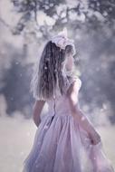 girl in a dress under snowfall in a fairy forest