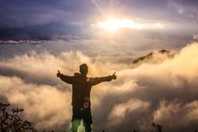 free man on top of the mountain in the clouds at the sunlight