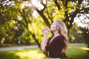 girl prays on a background of green wood