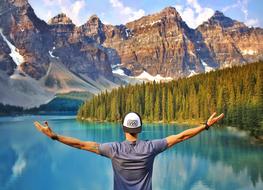 Man with wide open hands at scenic mountain lake, canada