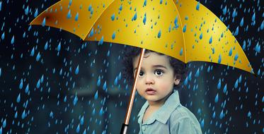 photo of a child under a yellow umbrella in the rain