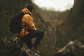 Man in yellow jacket sits on rock