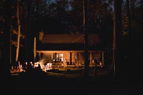 people resting at campfire in forest near Cabin