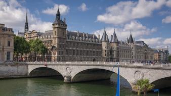 Beautiful architecture, river and green plants, under the blue sky with white clouds, in Paris, France