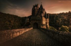 road with stone walls and pavement to medieval castle at dusk