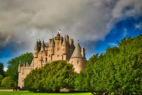 castle with towers behind green trees