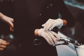 female hands in white gloves on handlebar of vintage bicycle