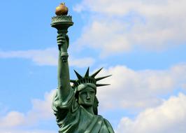 sky with white clouds over the statue of liberty