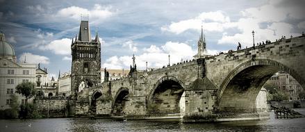 Beautiful landscape of the old Charles Bridge in Prague, Czech Republic, among the buildings, under the blue sky, with clouds