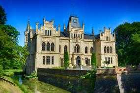 Beautiful Castle Evenburg, among the water and colorful plants, at blue sky in East Frisia, Germany