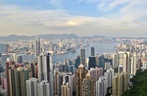 Cityscape of Hong Kong, with the colorful buildings, on the shore, from the Victoria Peak, under the blue sky, with the clouds