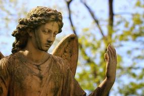 Beautiful statue of angel among the green trees on the cemetery