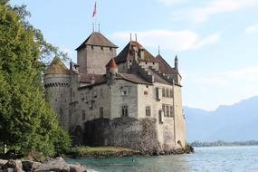 old castle with a flag at the water's edge