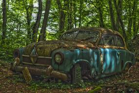 abandoned rusty Oldtimer Car beneath trees at summer