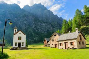 houses and a chapel against the backdrop of the Alpine mountains, italy